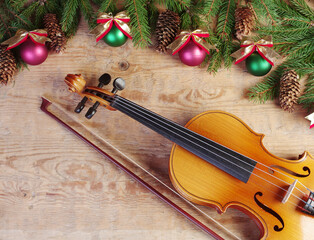 Violin and bow, fir branch and Christmas decorations on a wooden background. © yrafoto