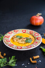 Delicious healthy pumpkin soup, herbs, and ingredients for the dish. Creative atmospheric decoration