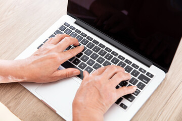 Old man's hand typing input on a computer keyboard