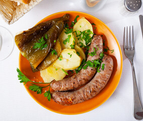 Tasty fried pork sausages with baked potatoes and pepper at plate
