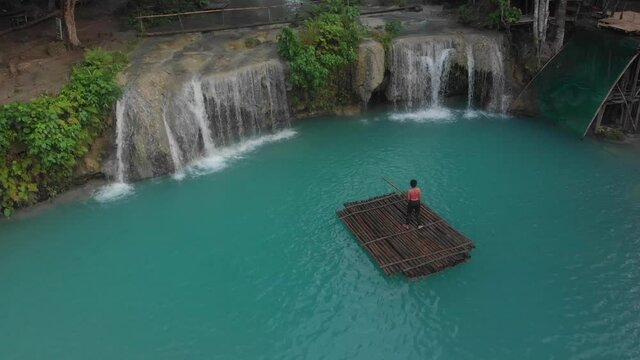 Woman is standing on a bamboo raft at the Cambugahay Falls the Philippines on a early morning Cinematic Drone Aerial in 4K