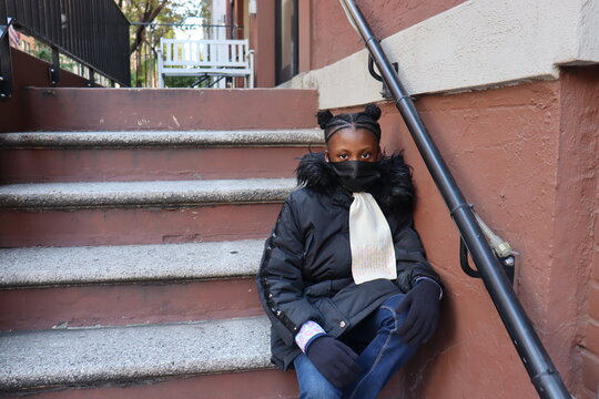 Student Sitting On City Brownstone Steps Wearing Black Face Mask