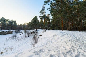 Winter landscape in the forest at sunset. Lots of footprints in the snow. Snow-covered quarry