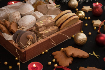 New Year and Christmas photo of box filled with homemade cakes on black background, with decorations and baking around.