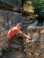 guy rested his foot on a stone fence and wants to pull out a sprouted tree root from it