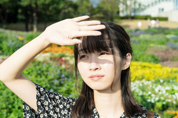 Naklejka premium まぶしい太陽光を手でさえぎるアジア人の若い女性
