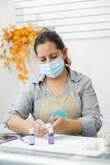 Pastry chef working with fondant to decorate a cake - Woman cooking with mask - Woman painting clay...