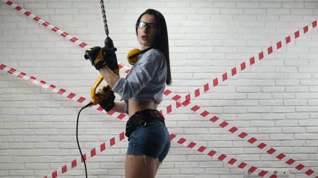 sexy woman in the image of a construction worker in short shorts holding a puncher
