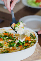 Housewife lays on plates traditional pumpkin pie with turkey and baked vegetables.
