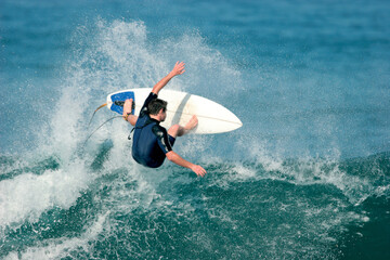Obraz na płótnie Canvas A surfer boosts a radical aerial move on a wave in the ocean. Slight motion blur.