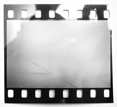 single 35mm film strip or snip isolated on white background with cool light or flash reflection. 