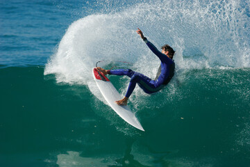 A surfer carves a radical cutback and sends spray flying on an ocean wave.