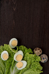 Fototapeta na wymiar Quail eggs and lettuce on a dark wooden background. Delicious and healthy Breakfast, lifestyle, ingredients for cooking different dishes. Photo of food.