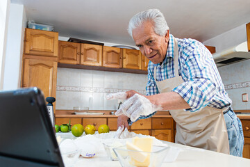 An old man using a tablet and cooking bread