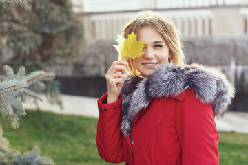  blond business woman in red fox fir dawn jacket with hood closeup photo on city park background