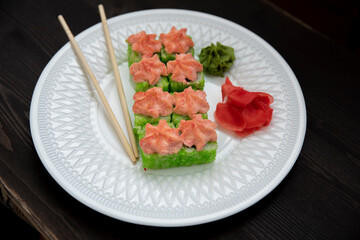 Set of eight sushi rolls on a white plate with salmon, eel, tuna, avocado, king prawn, cream cheese, tobiko caviar, Chuka. The sushi menu. Japanese cuisine. Top view of assorted sushi.