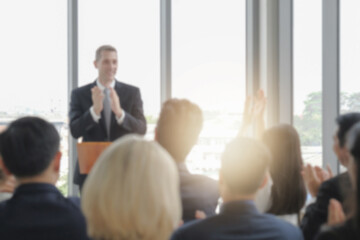 Blur photo background of happy business audience and speaker in corporate seminar event clapping hands together for celebration or congratulation, light effect. - obrazy, fototapety, plakaty