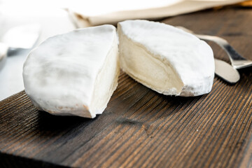 A type of Brie cheese. Camembert cheese. Fresh Brie cheese cut into pieces on a wooden board. Italian, French cheese. Close-up