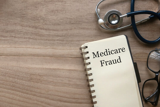 Top View Of Stethoscope, Glasses And Notebook Written With Medicare Fraud On Wooden Background With Copy Space.