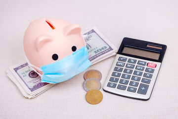 pink piggy bank in medical mask with dollars and calculator