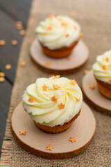 Cupcakes with swirling glaze on wooden supplies and burlap.