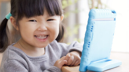 リビングでタブレットを見る子供