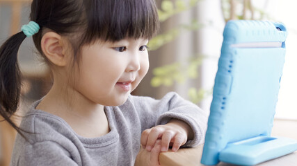 リビングでタブレットを見る子供