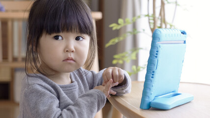 リビングでタブレットを見る子供