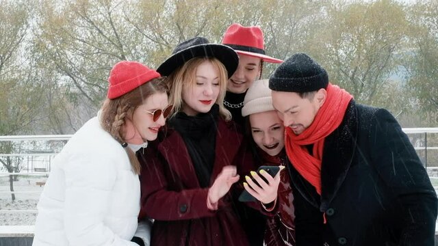 Happy smiling people using modern technology smartphones. Media, lifestyle, internet education concept. enjoying a meeting in the city in winter. Fool around, play around.
