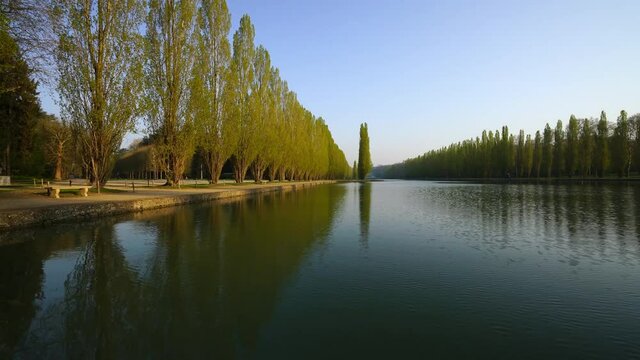 Lake view of French park in spring, orderly trees' reflection in the water
