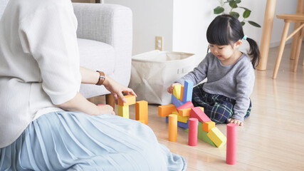 リビングで積み木で遊ぶ子供と親