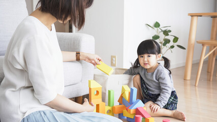 Obraz premium リビングで積み木で遊ぶ子供と親
