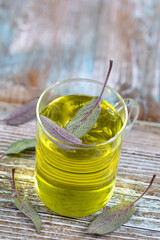 Cup of herbal sage tea with fresh leaves on rustic background , health concept, close up