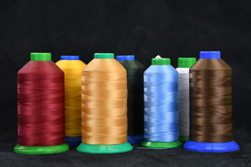 Set of colored threads for sewing on coils. Pile of big colorful spools of thread. Colored thread spools of thread large class, textiles, background