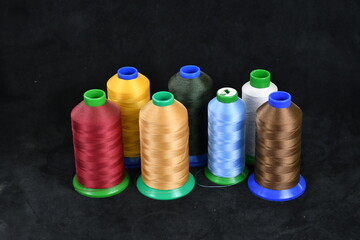 Set of colored threads for sewing on coils. Pile of big colorful spools of thread. Colored thread spools of thread large class, textiles, background