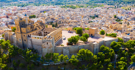 Aerial view of fortified castle and Basilica of Vera Cruz on hill dominating residential areas of Spanish town of Caravaca de la Cruz on summer day