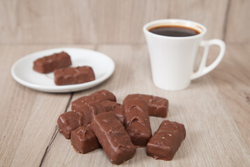 Delicious chocolate candies with coffee on a wooden background.