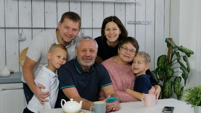 Happy big family woth grand parents and adul children, several generations in the kitchen smiling