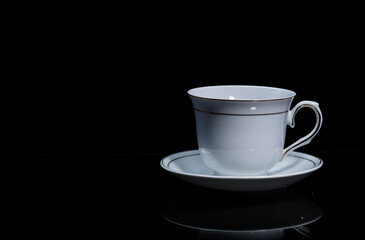 White Cup and saucer on a black background.
