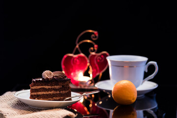 Obraz na płótnie Canvas A piece of chocolate cake on a saucer on a black background.