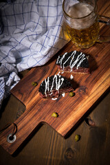 Gourmet Rindertatar Beef Tatar roh aus Filet fettarm, Kapern, Eigelb, Zwiebeln auf Toast Brot und schwarzer Kaviar, Schmand mit Bier, Küchentuch und Holzbrett Hintergrund dunkel