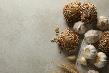 Fresh baked garlic buns and wheat ears on light gray table