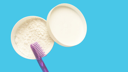 toothpowder and toothbrush on a blue background