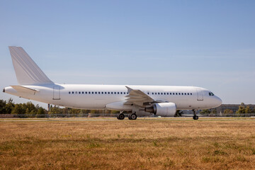 A white plane on the airport runway is taxiing. Takeoff and landing. Arrival and departure. Place for text. Passenger plane isolated mockup. Airplane landing. Travel by air transport. Copy space.