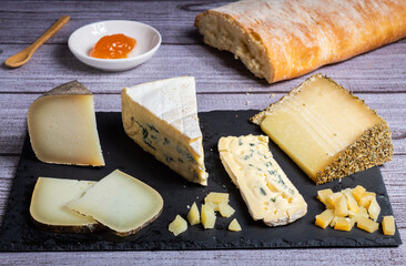 Variedad de quesos con pan y melmelada de decoración, en un fondo gris elegante