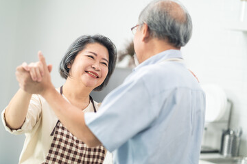 Obraz premium Asian senior couple dancing in the kitchen, Happy living retirement.