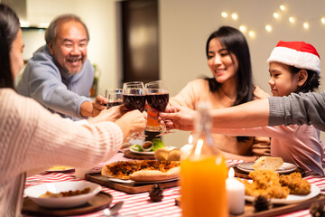 Asian big family clinking wine glasses and enjoying Christmas party.