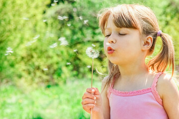 happy child playing and blowing dandelion in nature