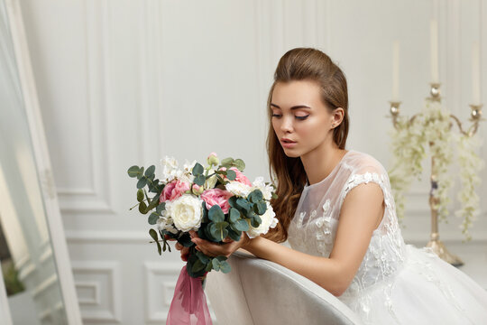 portrait of beautiful tender young bride with flower bouquet in studio interior