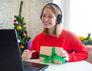 Christmas online congratulations. Smiling woman using laptop for video call friends and parents.